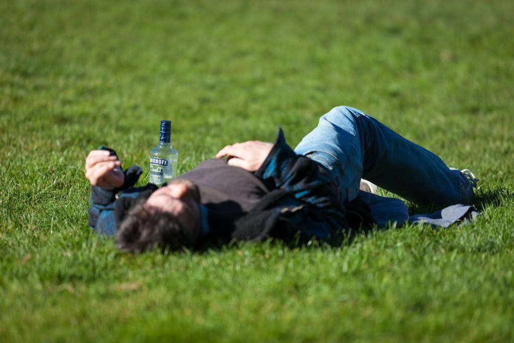 a man laying in the grass with a bottle of beer.jpg