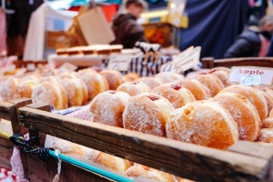 selective focus photography of doughnuts display on brown wooden trays near person wearing black hoodie.jpg