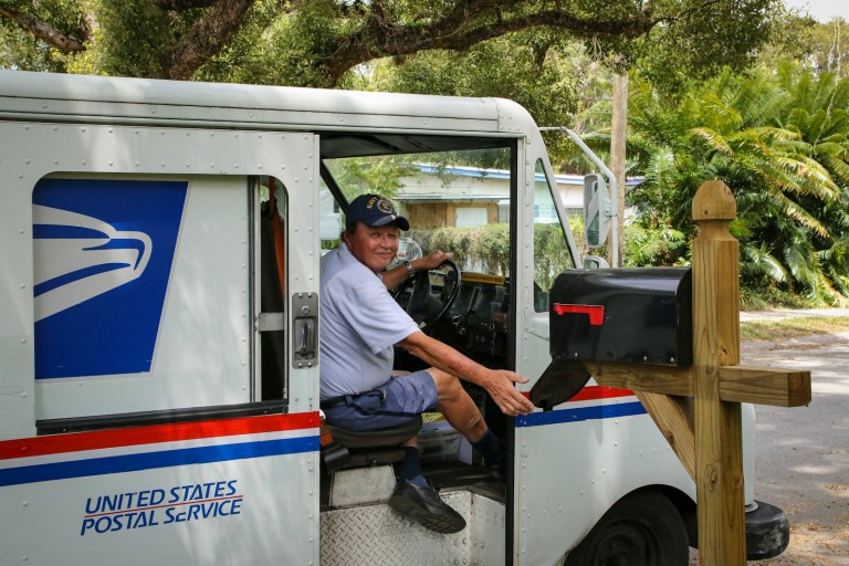 man in blue dress shirt sitting on white and blue bus during daytime.jpg