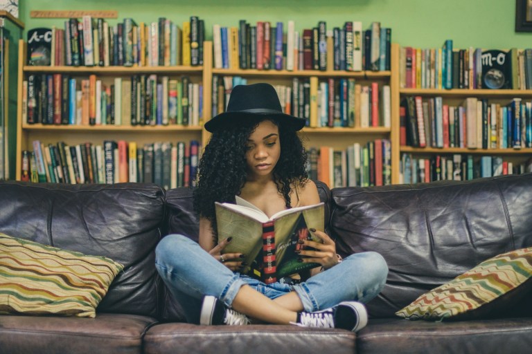 woman reading a book while sitting on black leather 3-seat couch.jpg