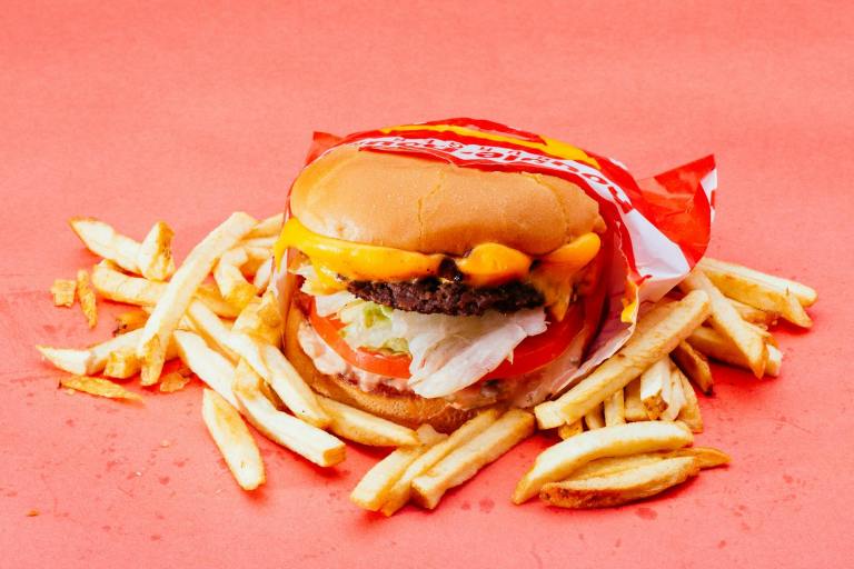 Tasty cheeseburger with fresh ingredients and french fries on a vibrant red background..jpg