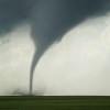 a large tornado is seen in the sky over a green field.jpg