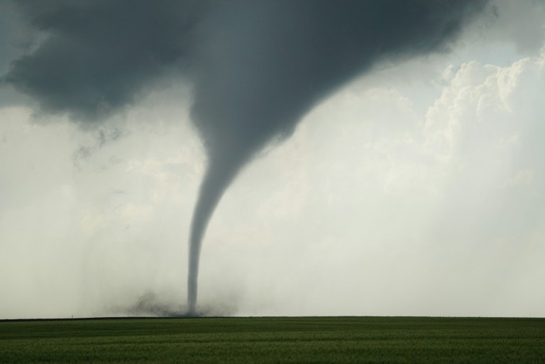 a large tornado is seen in the sky over a green field.jpg