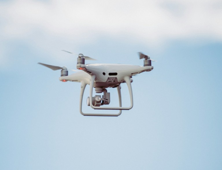 white DJI drone in mid air.jpg