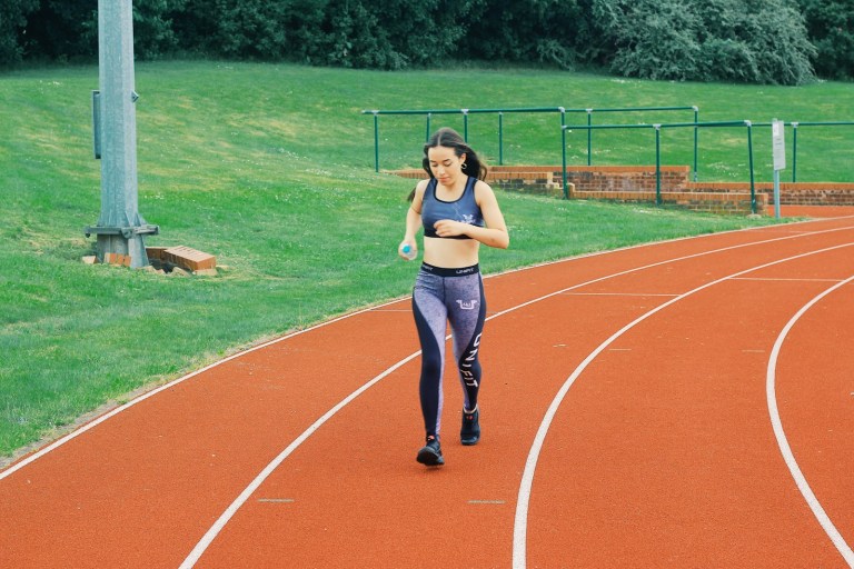 woman in black sports bra and blue denim jeans standing on track field during daytime.jpg
