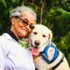 Elderly woman embracing her service Labrador Retriever outdoors, showcasing companionship..jpg