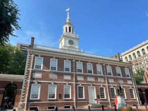 a large brick building with a clock tower with Independence Hall in the background.jpg