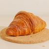 a croissant sitting on top of a cork coaster.jpg