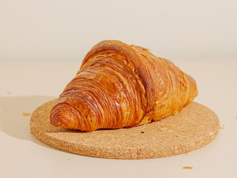 a croissant sitting on top of a cork coaster.jpg
