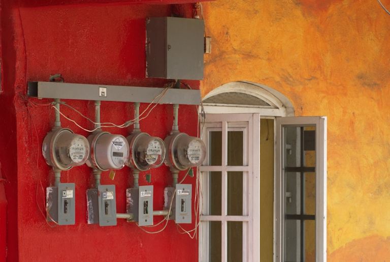 Four electric meters mounted on a red wall..jpg